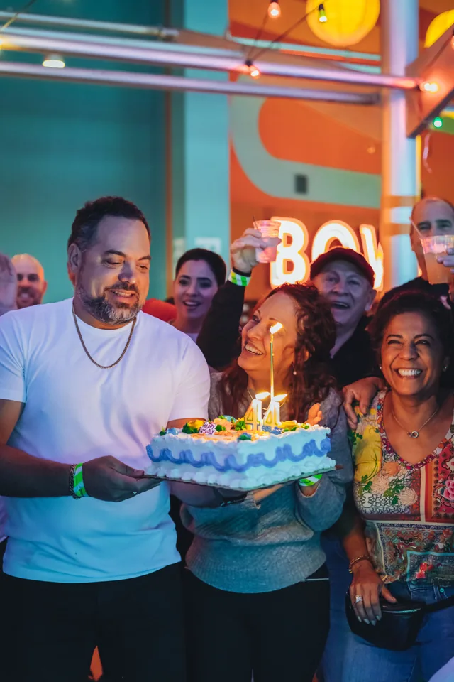A group gathered around a birthday cake with lit candles