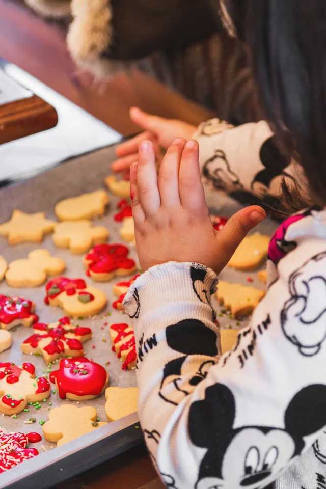 A child decorating biscuits at the kitchen counter
