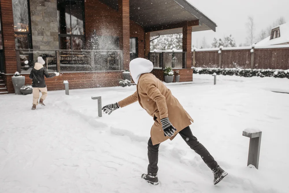 Children playing in the snow outside a house